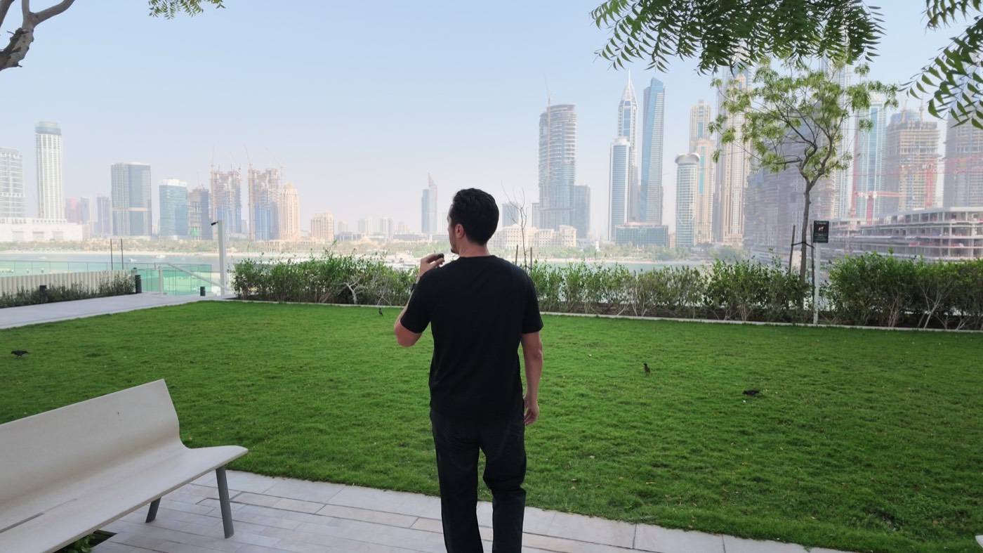 Clément Talmo dans le jardin d'une résidence à Dubaï, la skyline en fond